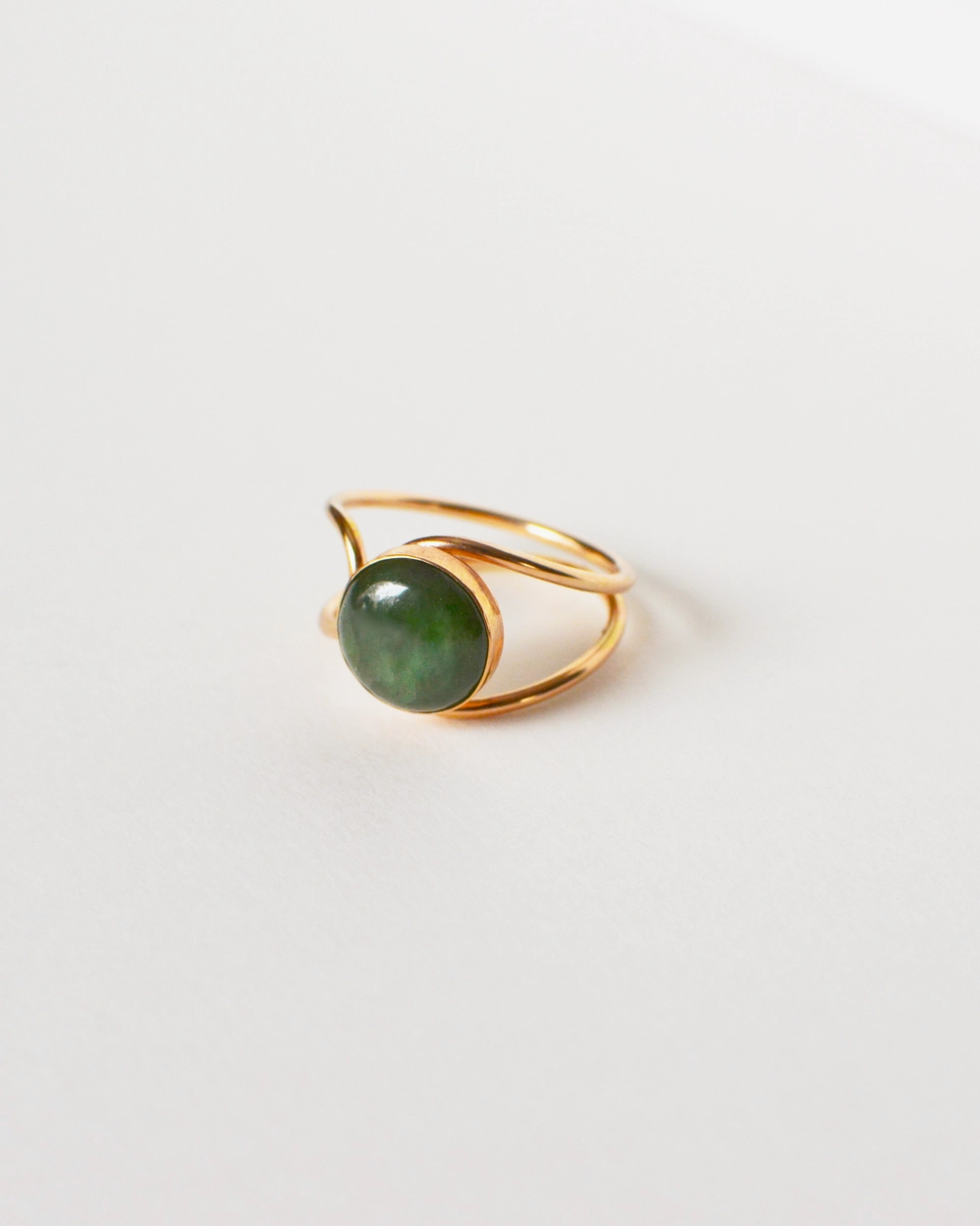 Gold ring with a green stone on a light gray background
