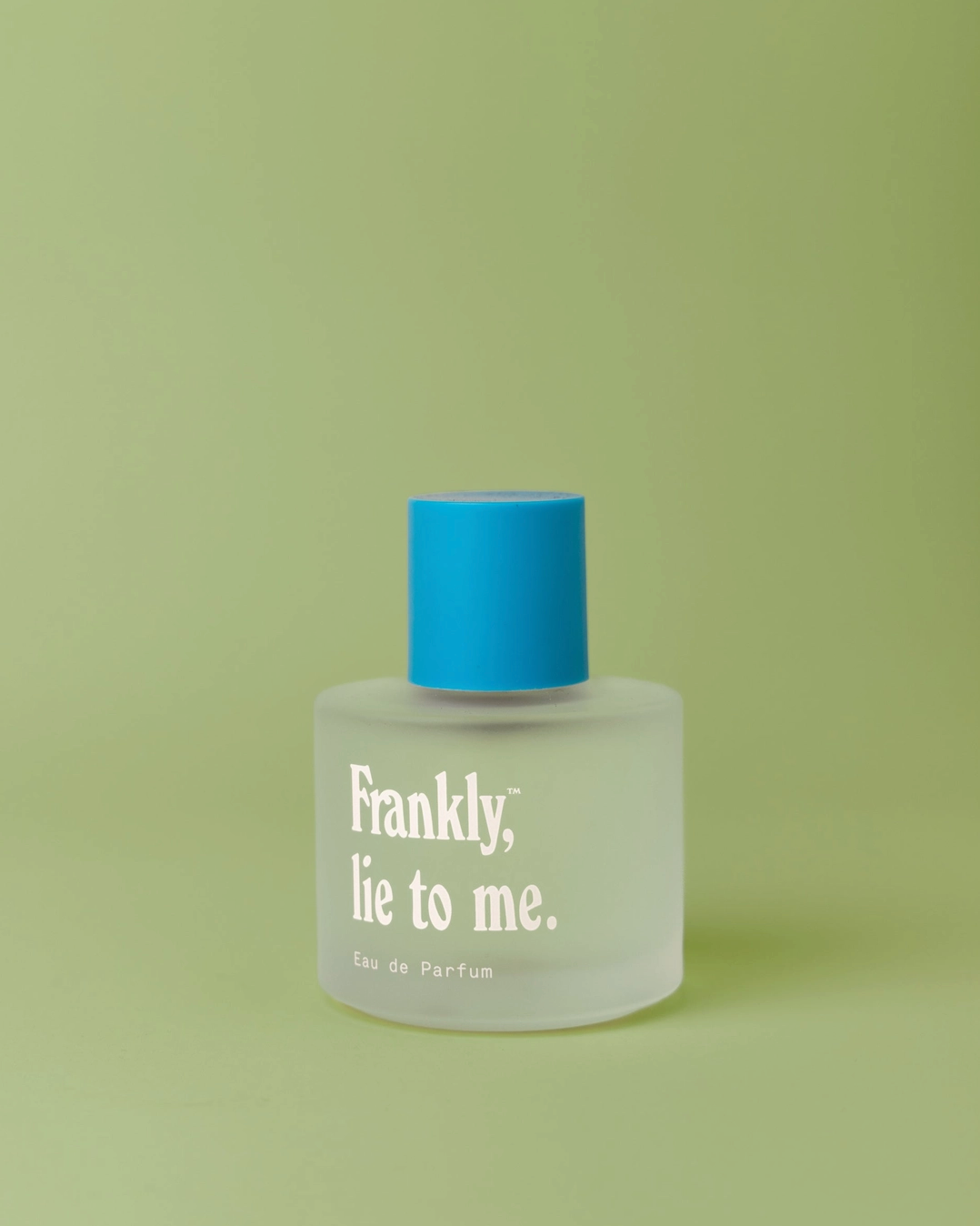Perfume bottle with blue cap and white label on a green background