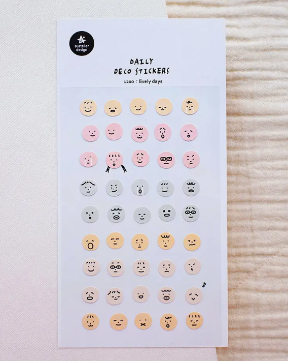 Sheet of decorative stickers with various face designs on a textured surface