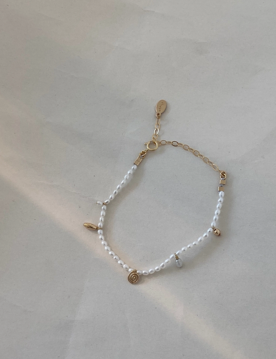 Bracelet with white beads and gold accents on a light gray background