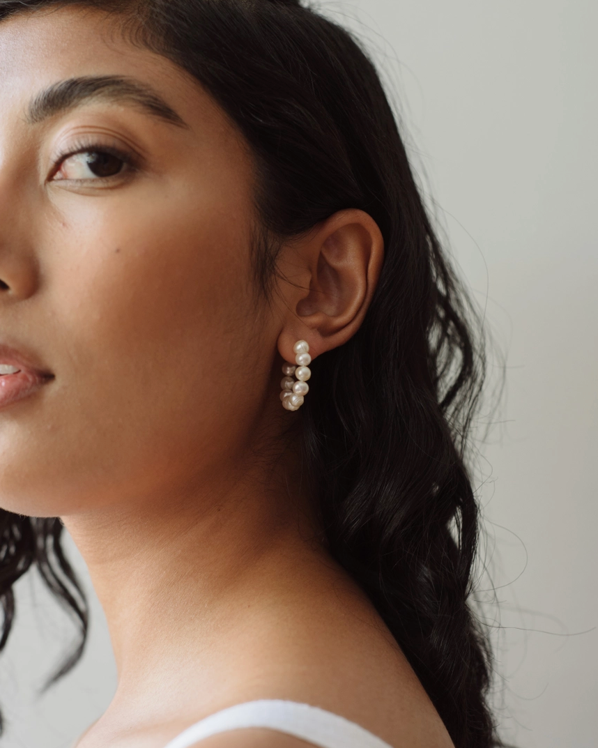 Woman wearing pearl earrings with a neutral background