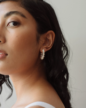 Woman wearing pearl earrings with a neutral background