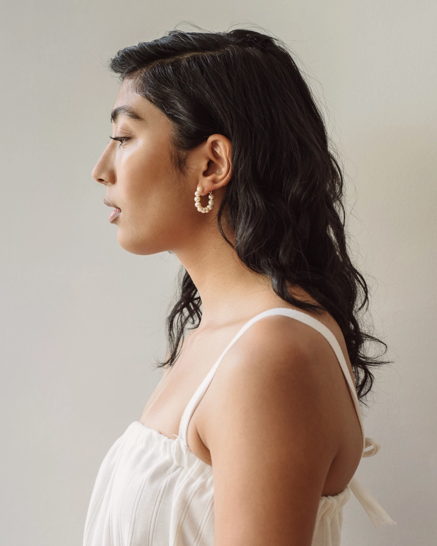 Woman wearing a white top with thin straps against a neutral background