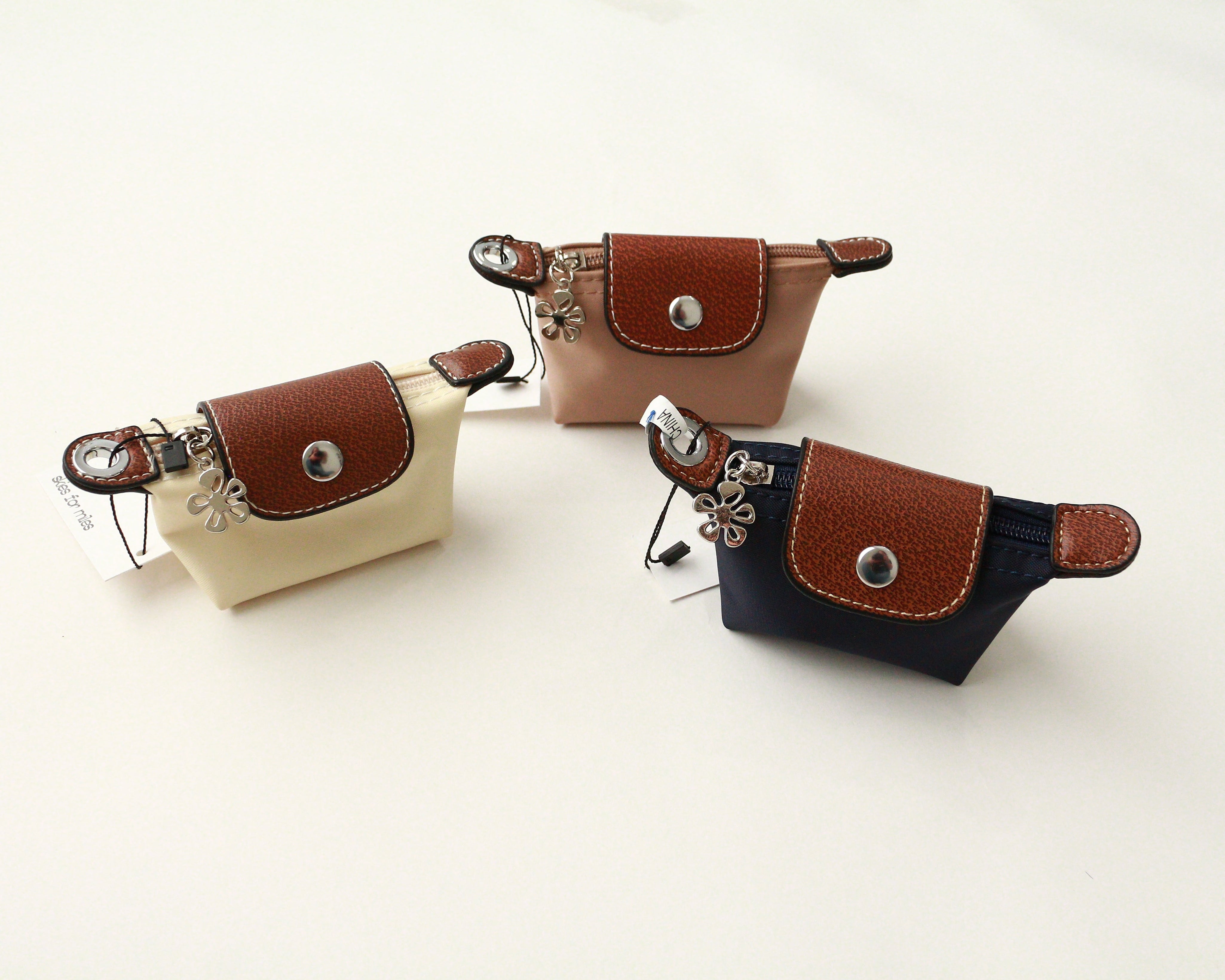 Three waist bags in beige, brown, and navy on a white background