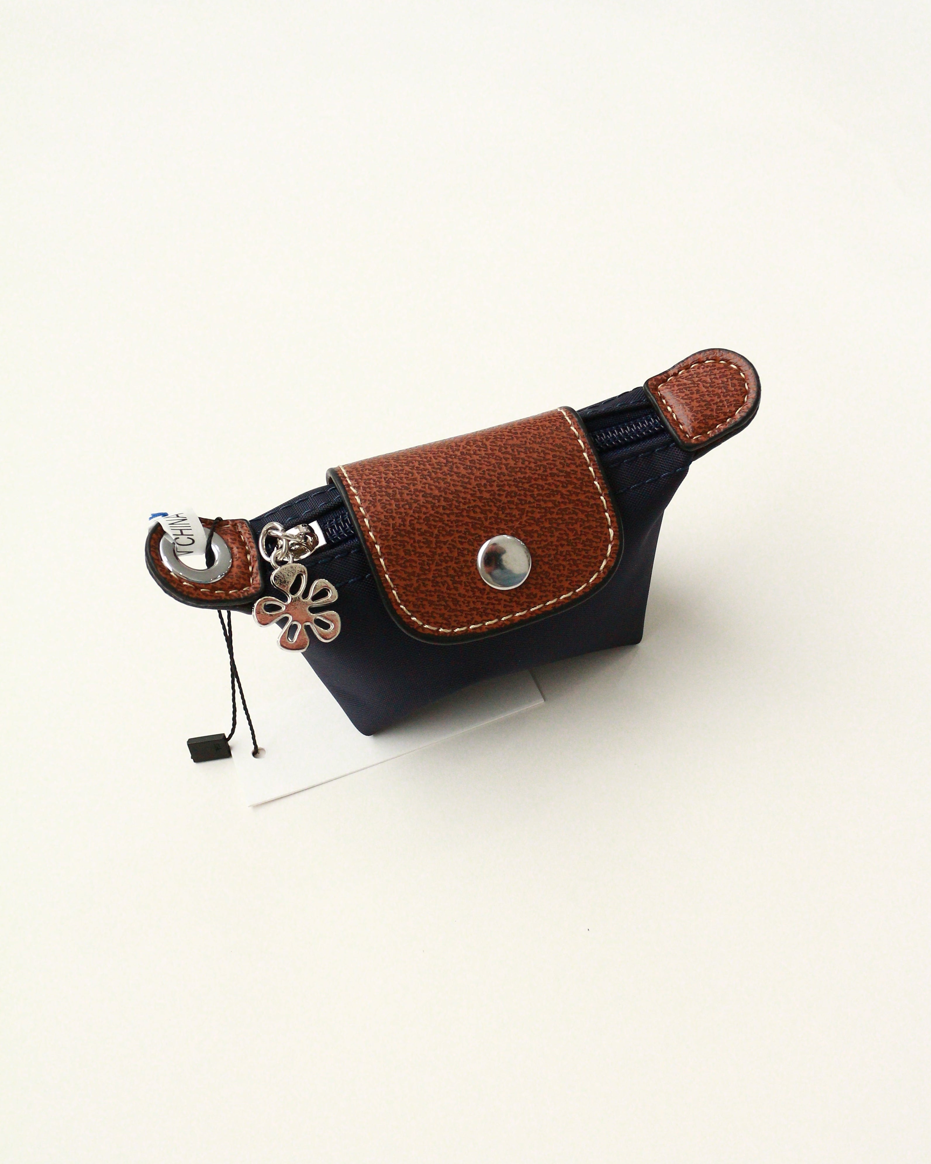 Brown and black leather key case with a flower charm on a white background
