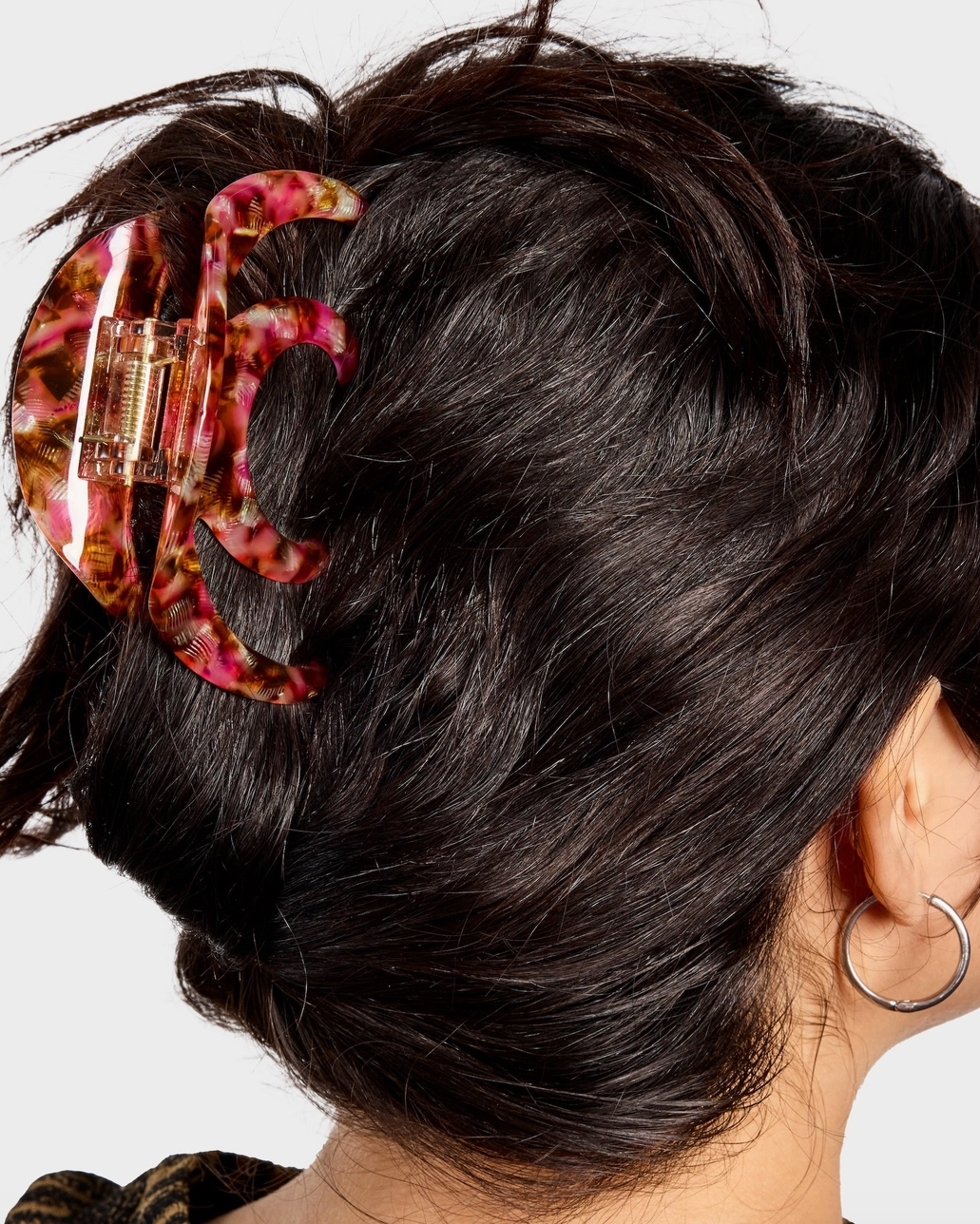 Close-up of a person's hair with a leopard print hair clip on a white background