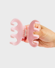 Hand holding a pink tool with a white background