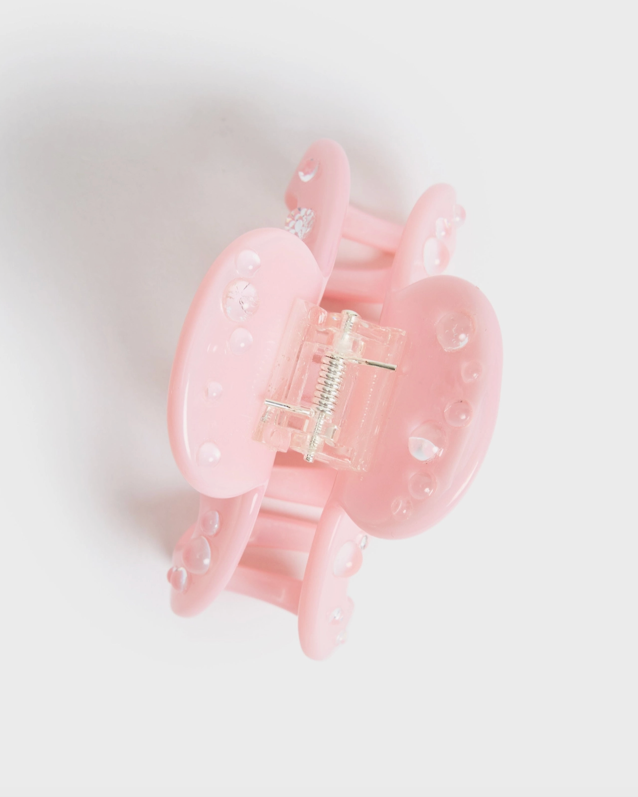 Pink hair clip with clear plastic center on a light gray background