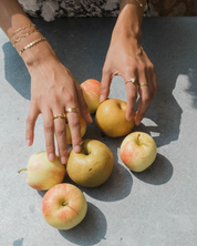 Hands with rings on a surface with apples