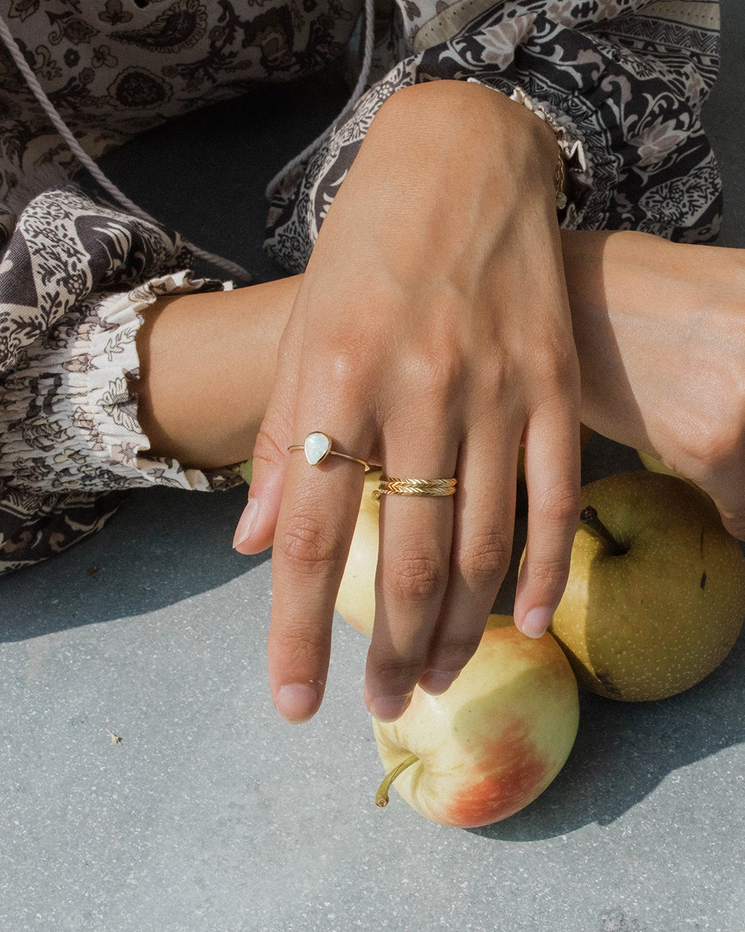 Close-up of hands with rings on a surface with apples