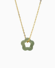 Necklace with a green floral pendant on a gold chain against a white background