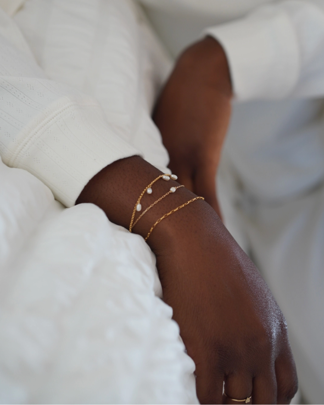 Close-up of a hand wearing gold bracelets on a blurred background