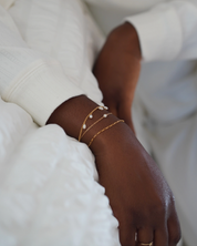 Close-up of a hand wearing gold bracelets on a blurred background