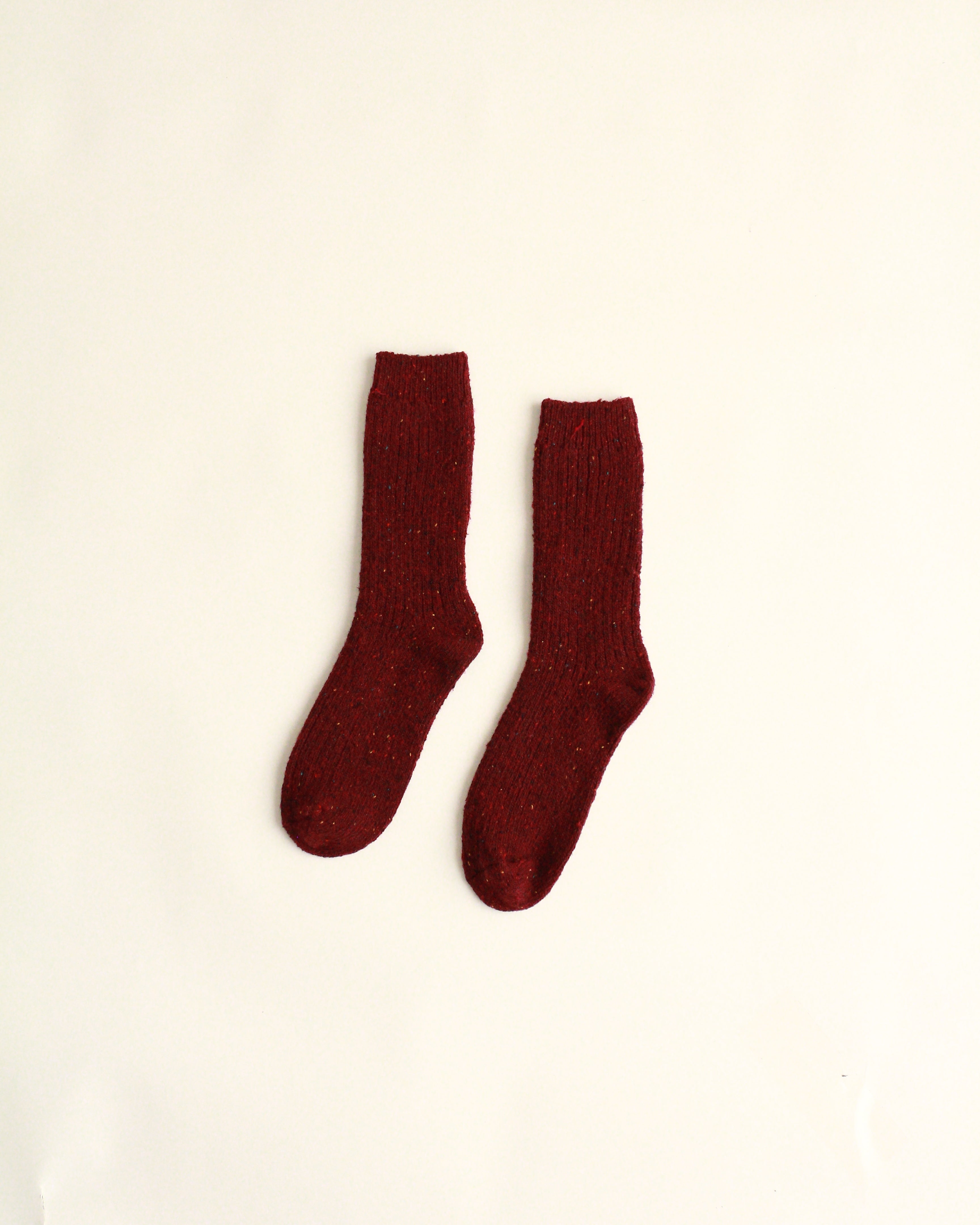Pair of maroon socks on a beige background
