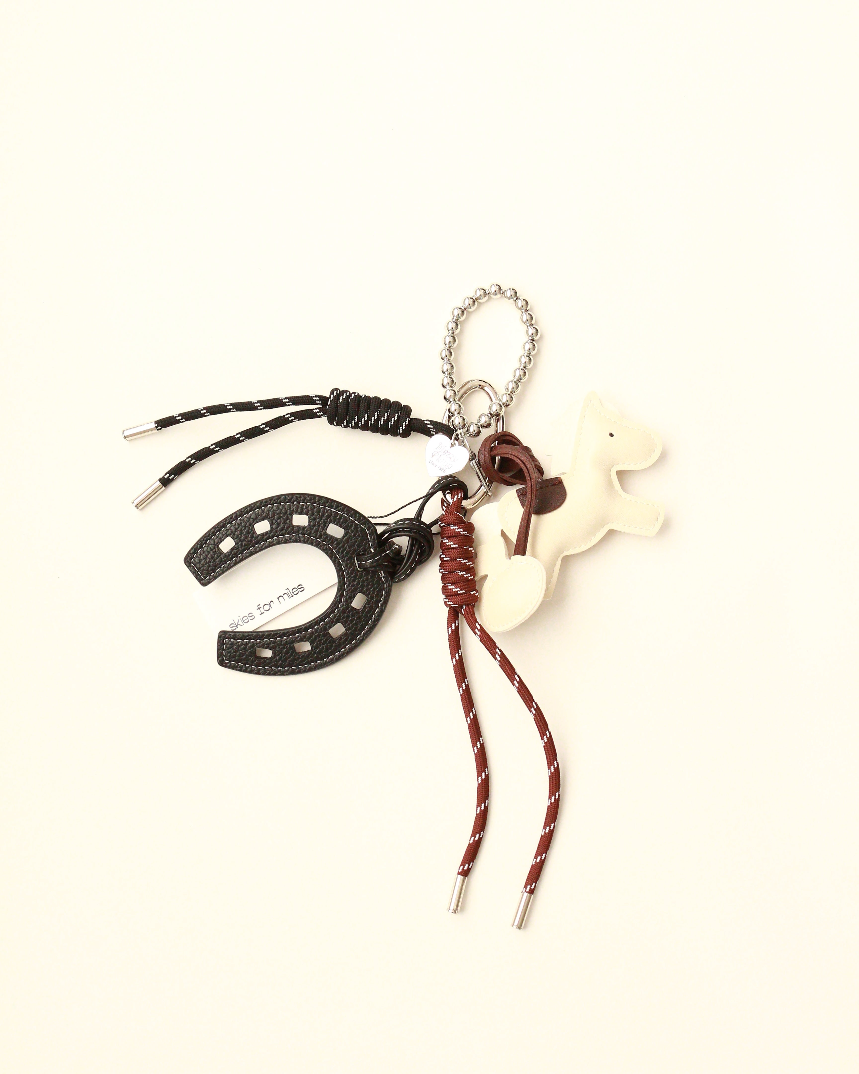 Keychain with horseshoe, horse figure, and braided cord on a white background