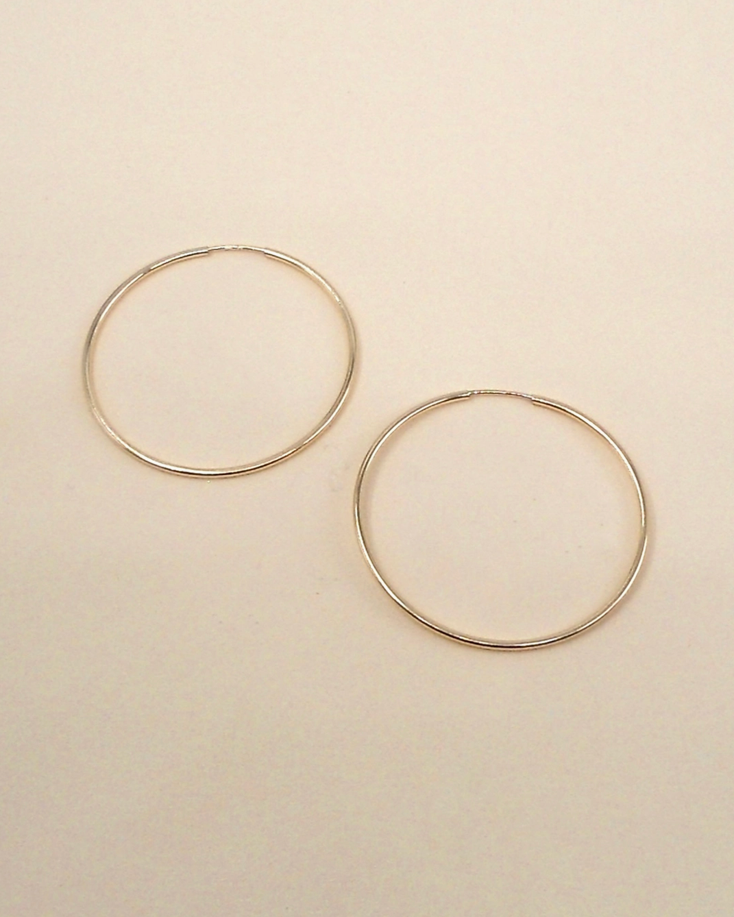 Gold hoop earrings on a beige background