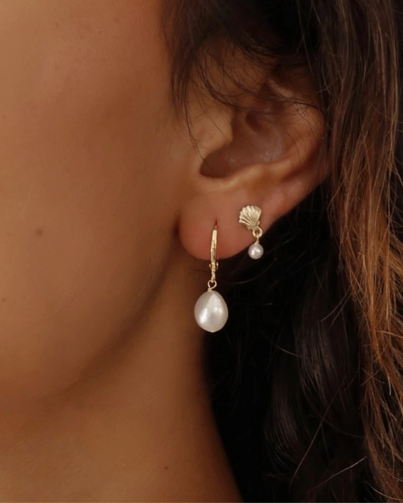 Close-up of a person wearing pearl earrings with a blurred background