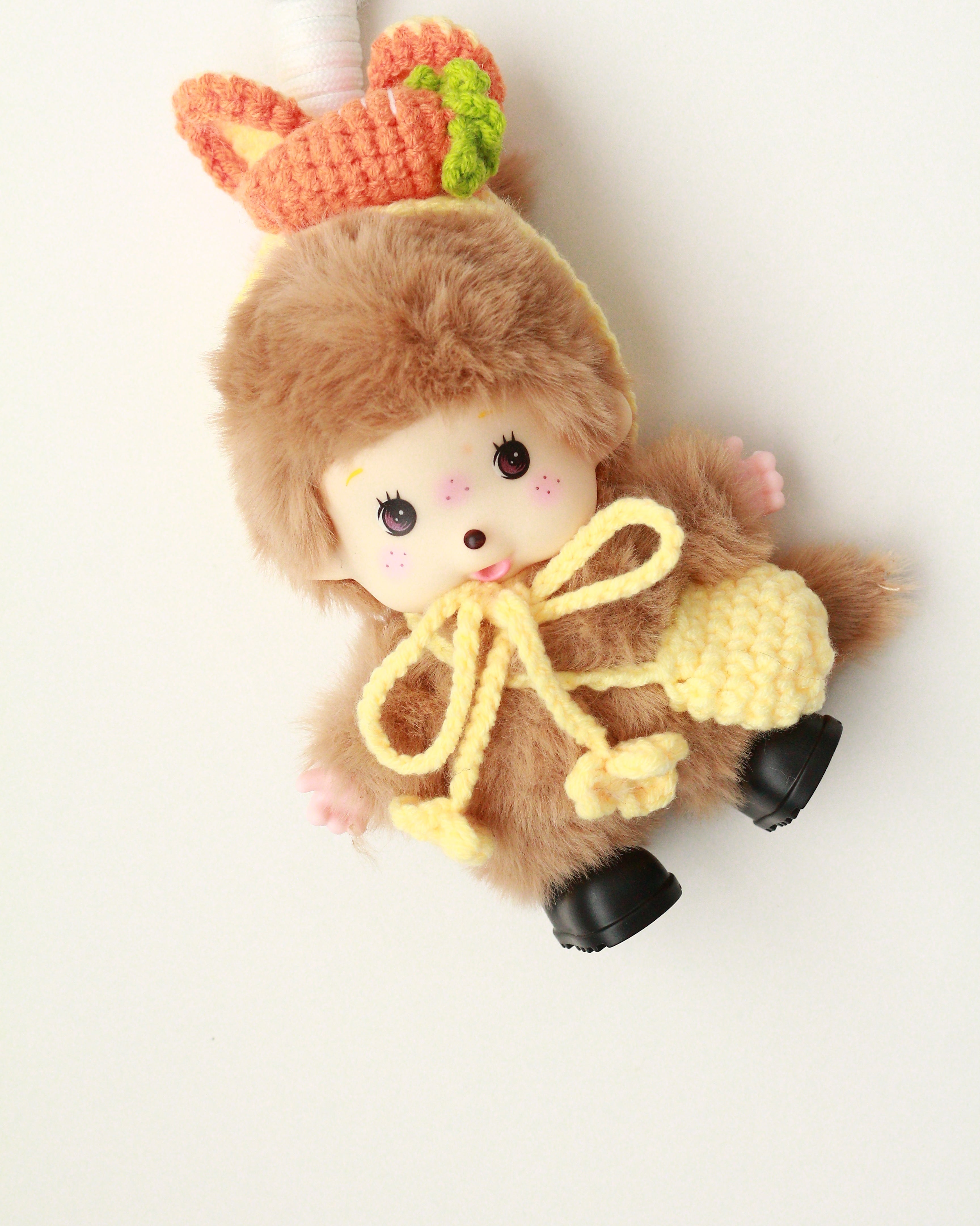 Small plush toy sloth with a camera on a white background