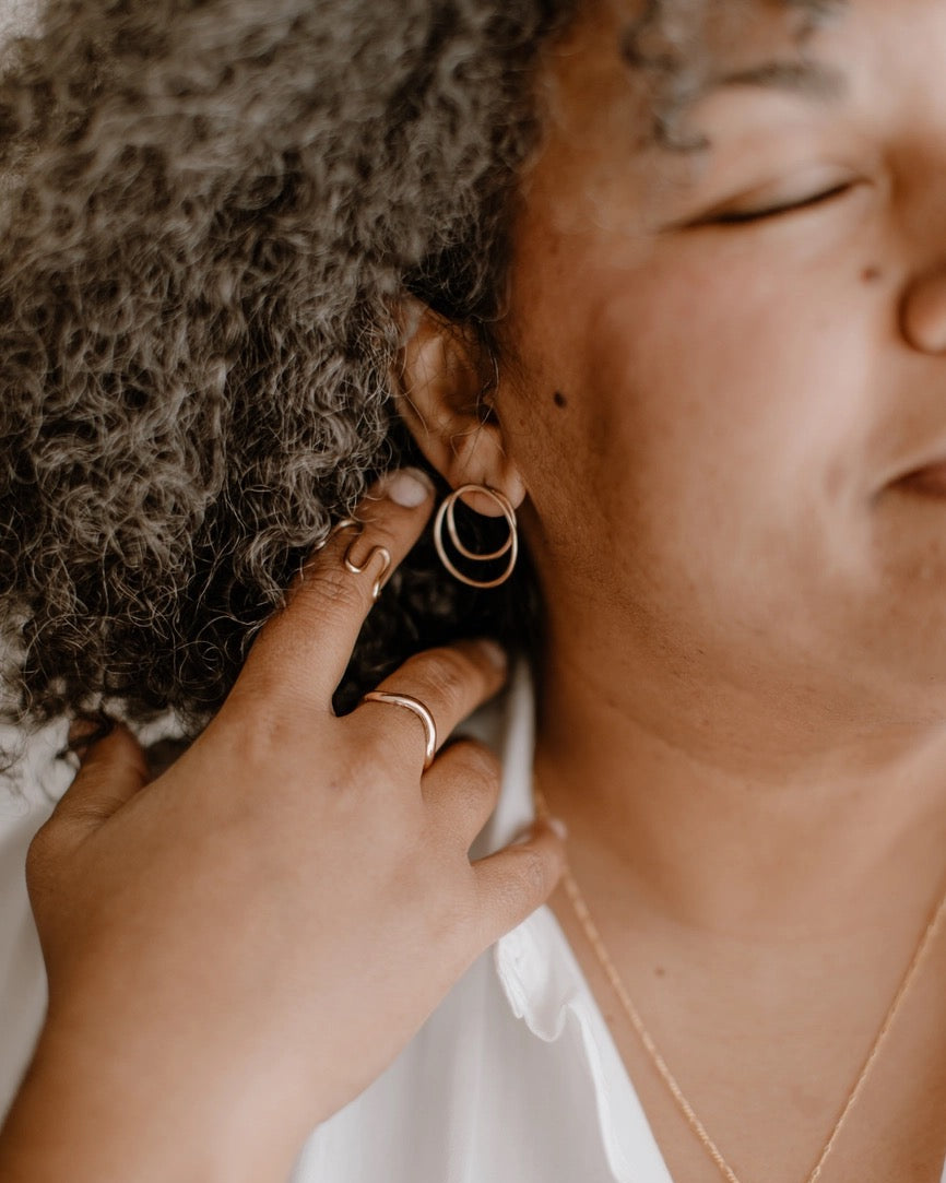 Person wearing gold hoop earrings and a necklace with a white shirt.