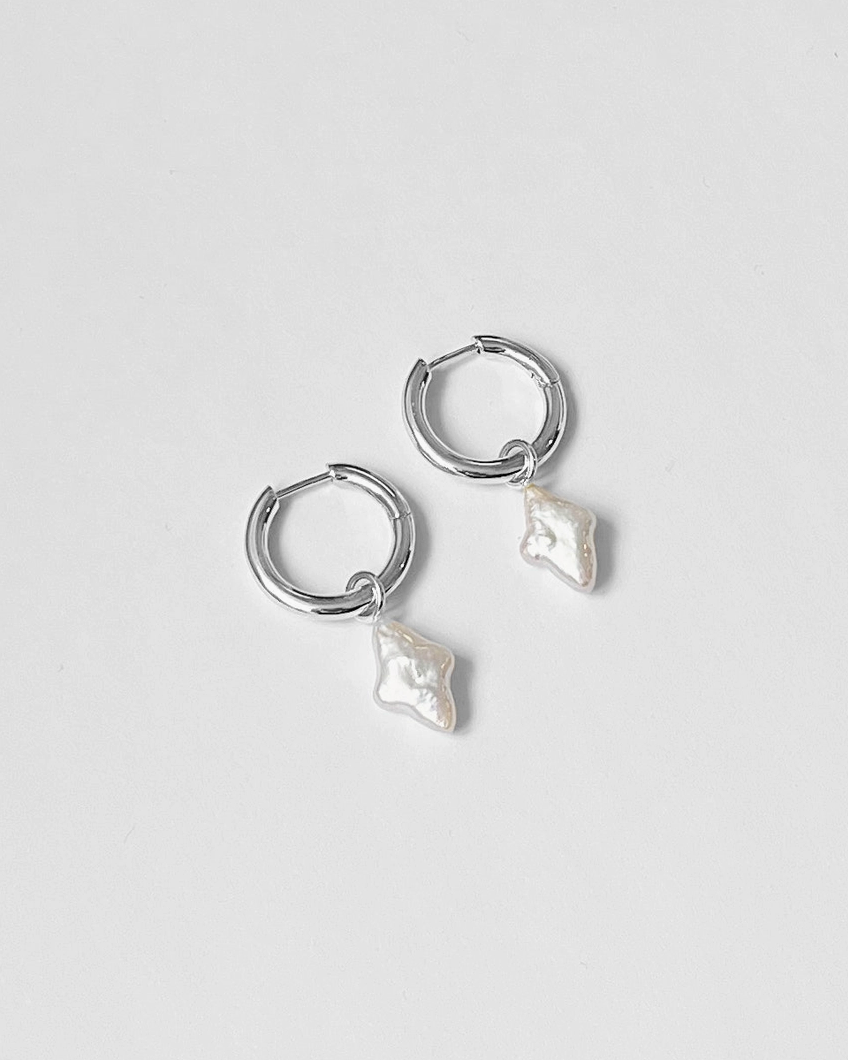 Pair of silver hoop earrings with pearl-like droplets on a light gray background