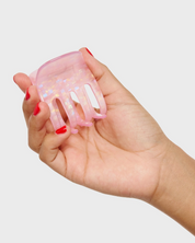 Hand holding a pink hair clip against a white background
