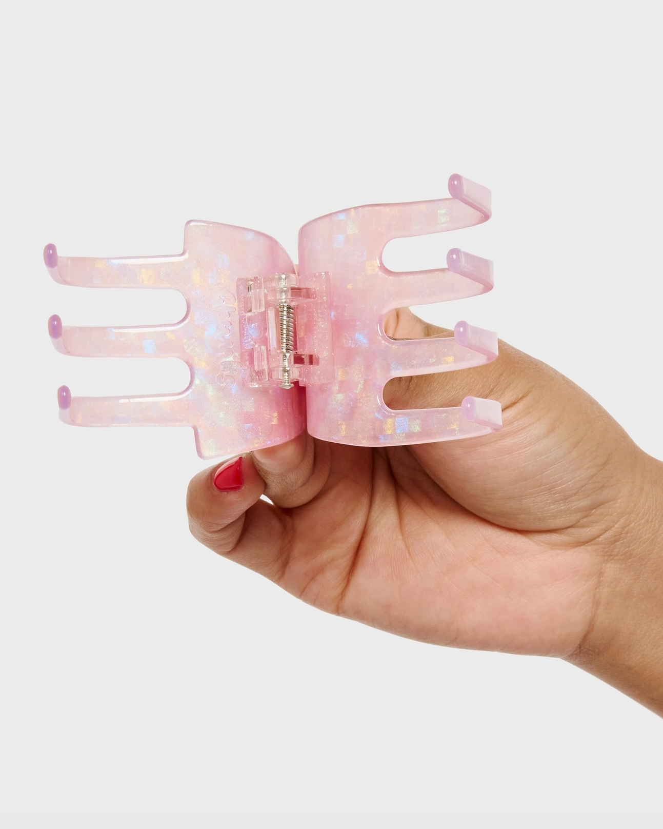 Hand holding a pink butterfly-shaped hair clip against a white background