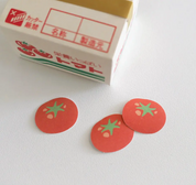Red tomato-shaped stamps with green leaves on a white background, next to a small box.